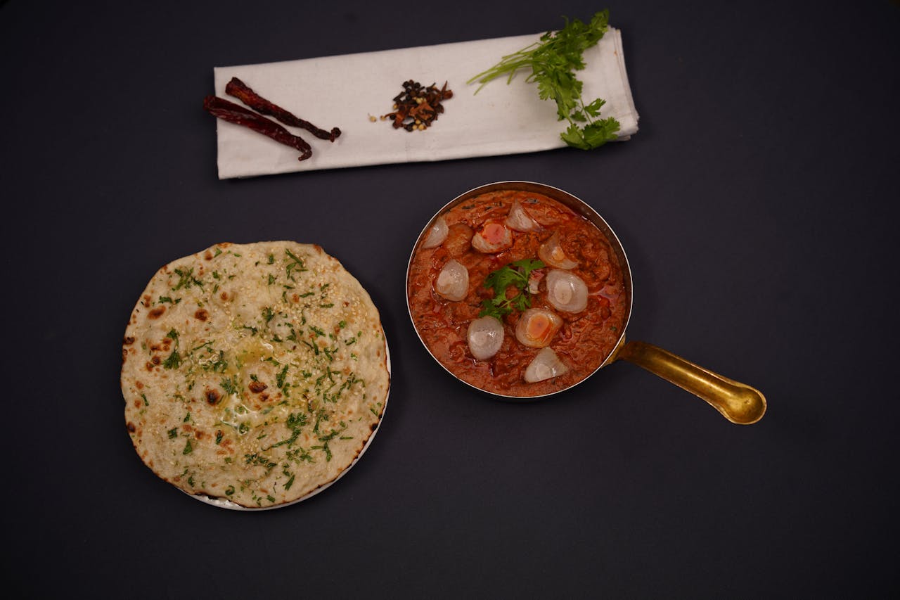 Authentic Indian curry served with naan bread, garnished with fresh herbs and spices.