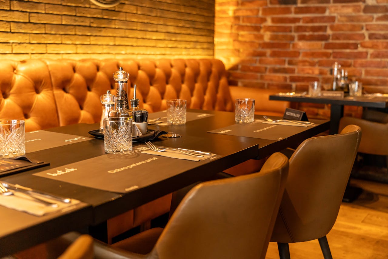 hero-img-02 Warm and inviting restaurant setting with elegant leather seating and table setting.
