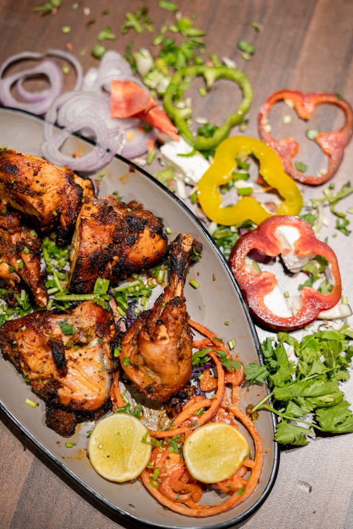 gallery-1 Savor the vibrant flavors of tandoori chicken with fresh vegetables, perfect for food photography enthusiasts.