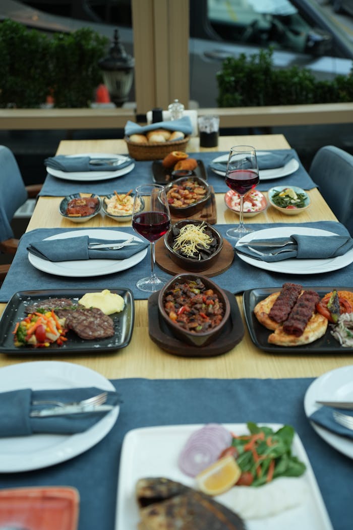 A beautifully presented dining table set with an array of gourmet dishes and glasses of wine in a restaurant setting.
